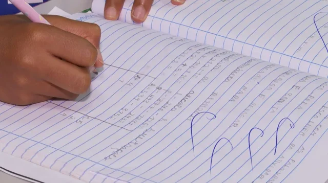 criança escrevendo em caderno